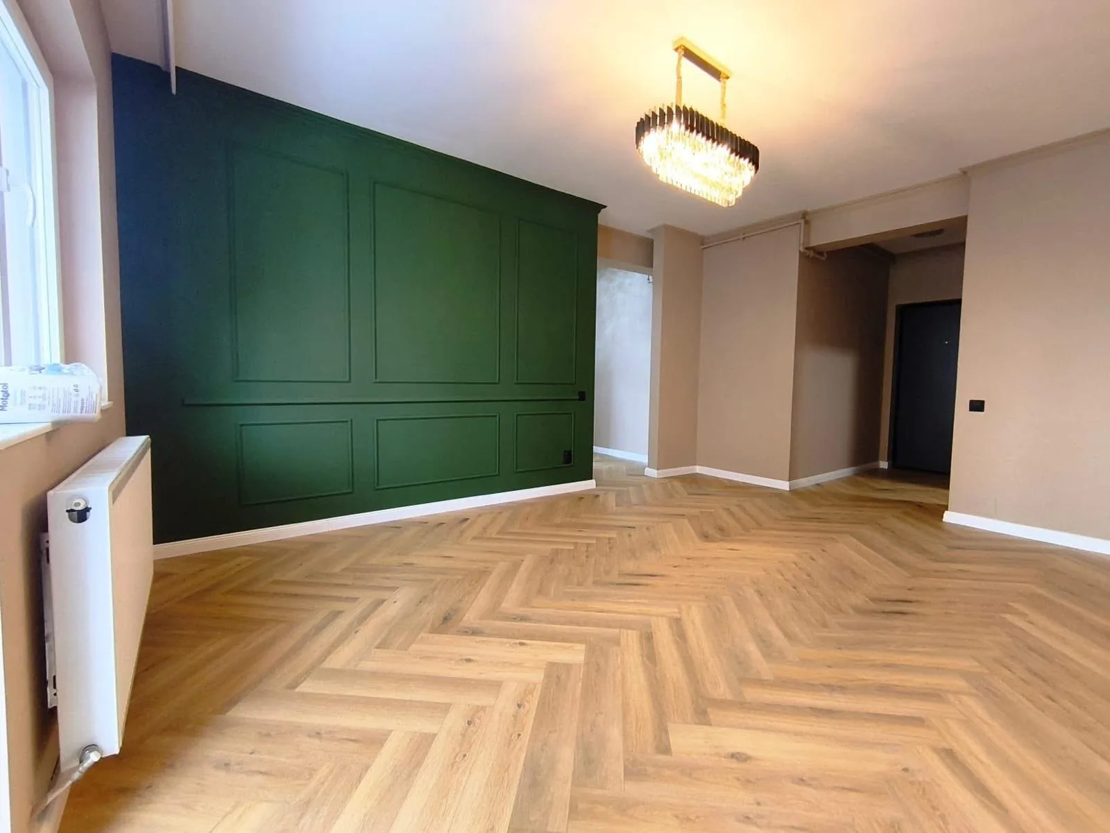 Oak herringbone floor beside dark green fitted wall panelling