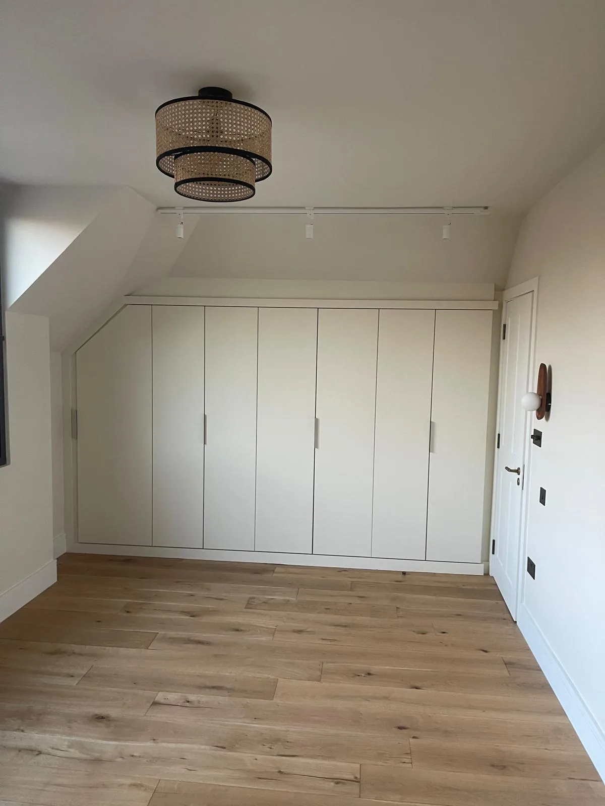 Wide-plank oak flooring in a bedroom with fitted wardrobes